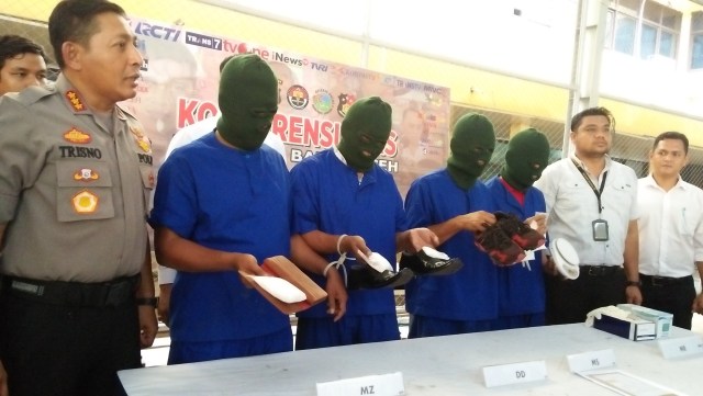 Empat tersangka pengedar sabu yang ditangkap personel Opsnal Sat Resnarkoba Polresta Banda Aceh memegang sepatu yang digunakan untuk menyimpan sabu pada konferensi pers, Senin (28/10). Foto: Husaini/acehkini