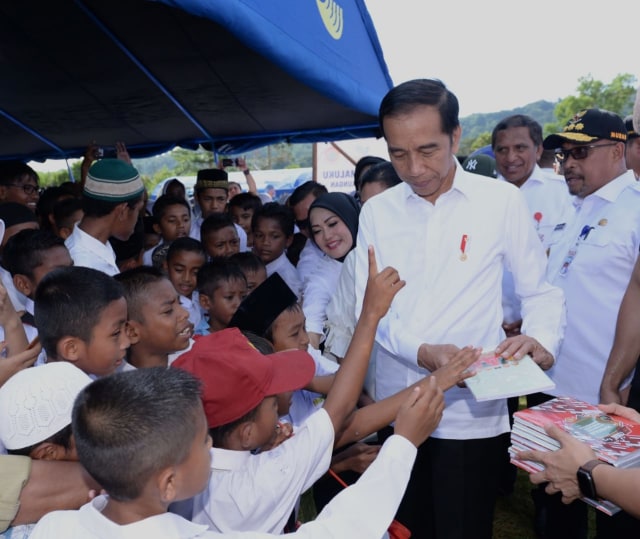 Presiden Joko Widodo membagikan buku kepada anak-anak di posko pengungsi pascagempa di Ambon, Selasa, (29/10/2019). Foto: Biro Pers Sekretariat Presiden/Kris