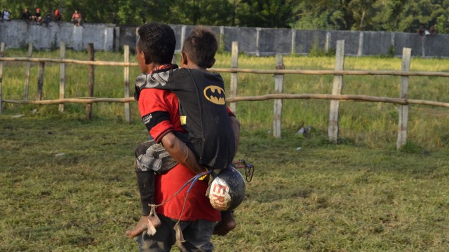 Seorang joki cilik sedang digendong ayahnya sebelum berpacu dalam arena. Foto: Muhammada Safirah/Info Dompu