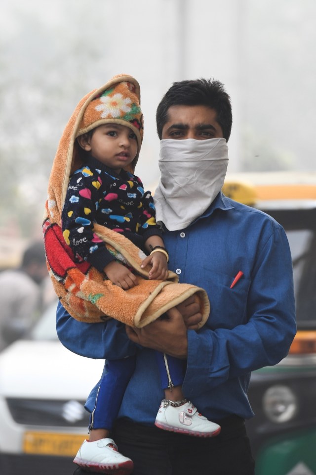 Warga mengenakan masker penutup hidung di tengah kabut asap di New Delhi, India, Senin (4/11/2019).
 Foto: AFP/PRAKASH SINGH