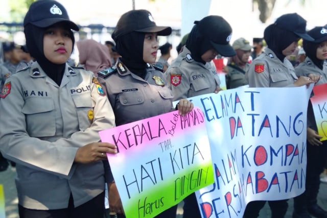Anggota Polwan Polres Sampang membentangkan poster saat mengamankan aksi demo di kantor Pemkab, Senin (4/11/2019) pukul 09.30 WIB. (Ryan/MM). 