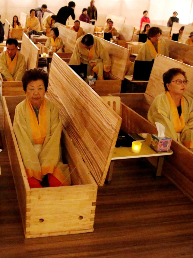 Peserta memasuki peti mati saat acara "living funeral" sebagai bagian dari program "dying well" di Seoul, Korea Selatan, Kamis (31/10/2019). Foto: REUTERS / Heo Ran