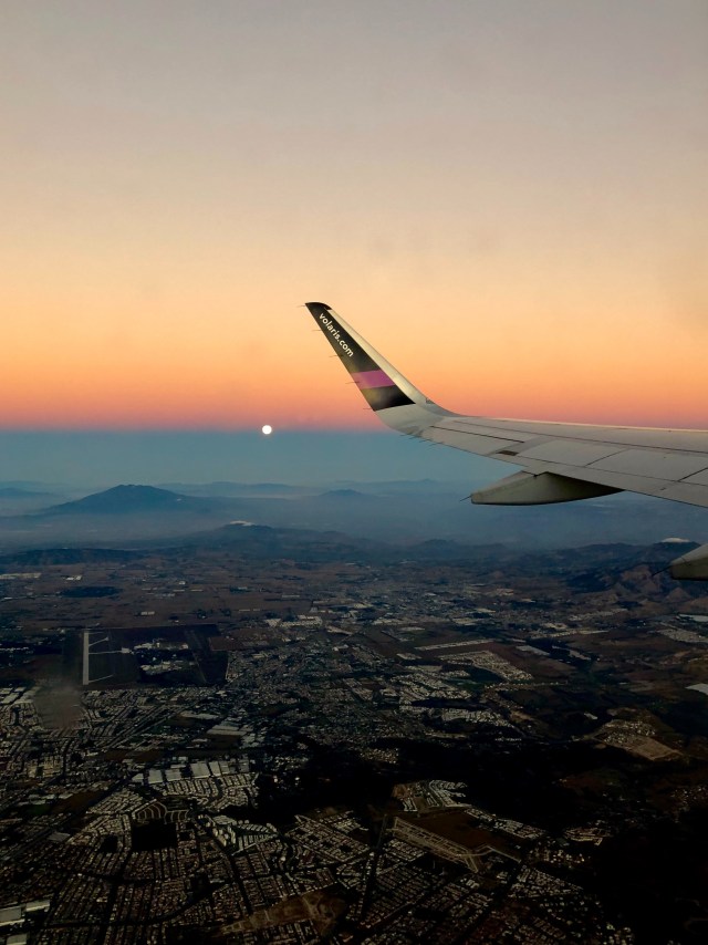 Ilustrasi pesawat yang tengah terbang jelang matahari terbit (portrait) Foto: Unsplash/Tess Broker
