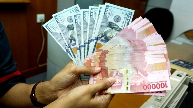 Pegawai menunjukan uang dolar Amerika Serikat dan rupiah di gerai penukaran uang Ayu Masagung di Jalan Kramat Kwitang, Senen, Jakarta Pusat, Kamis (7/11). Foto: Nugroho Sejati/kumparan