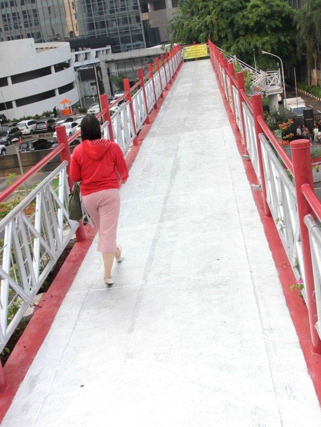 Pejalan kaki saat melintasi jembatan penyeberangan orang (JPO) yang tidak beratap di Jalan Sudirman, Jakarta. Foto: Irfan Adi Saputra/kumparan