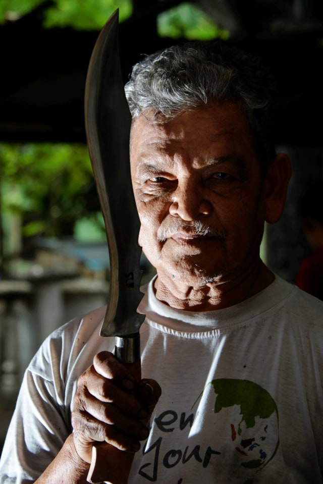 Pandai besi menunjukkan pisau yang sudah jadi di bengkel tradisional di Darul Imarah, Aceh. Foto: AFP/CHAIDEER MAHYUDDIN