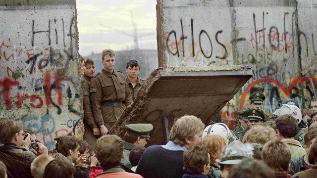 Warga Berlin Barat berkerumun di depan Tembok Berlin awal 11 November 1989 ketika mereka menyaksikan penjaga perbatasan Jerman Timur menghancurkan Tembok. Foto: AFP