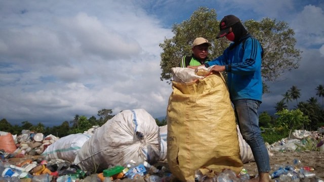 Dua pekerja tengah sibuk mengisi karung yang berisikan sampah plastik di antara tumpukan sampah yang berserakan di Tolitoli. Foto: Moh. Sabran/PaluPoso