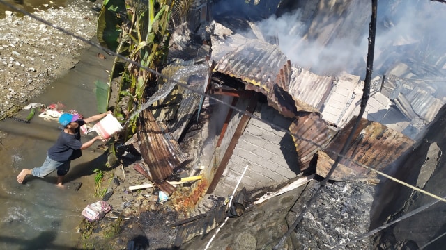 Salah satu warga penghuni kos-kosan di Jalan Emi Saelan, Kelurahan Tatura Selatan, Kecamatan Palu Selatan, Kota Palu nampak seorang diri menyiram salah satu kos yang masih terlihat titik api. Foto: Arief/PaluPoso