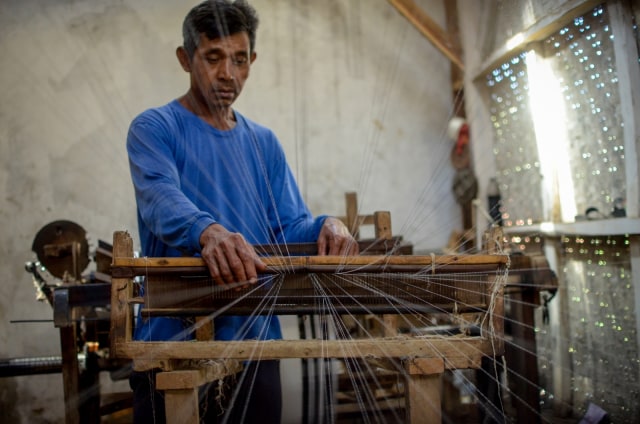 Perajin memintal benang untuk dijadikan kain pel di sentra industri tradisional Kampung Babakan, Desa Dukuh, Kecamatan Ibun, Kabupaten Bandung, Jawa Barat. Foto: ANTARA FOTO/Raisan Al Farisi