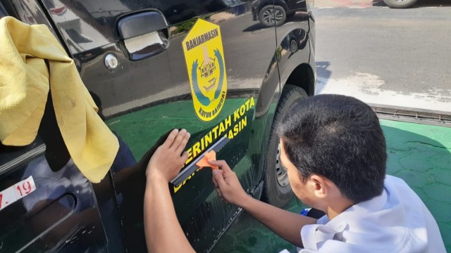 Pemasangan stiker pada mobil dinas Pemko Banjarmasin, Senin (18/11/2019). Foto: Syahbani/banjarhits.id