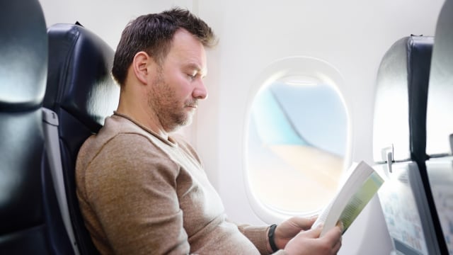 Ilustrasi penumpang pria duduk di bangku tengah pesawat Foto: Shutter Stock