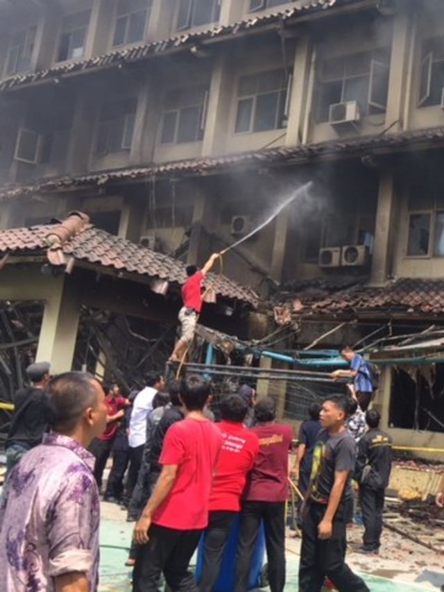Para guru dan petugas sekolah berusaha memadamkan api yang menyala di salah satu ruangan gedung belajar SMK Yadika 6, Kota Bekasi. Foto:  Andesta Herli Wijaya/kumparan 