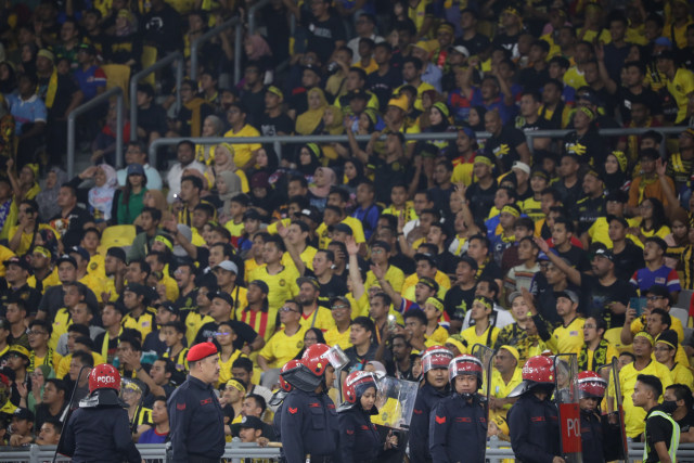 Polisi Malaysia berjaga didekat suporter Malaysia saat pertandingan Timnas Indonesia melawan Malaysia di Stadion Bukit Jalil, Malaysia. Foto: Jamal Ramadhan/kumparan