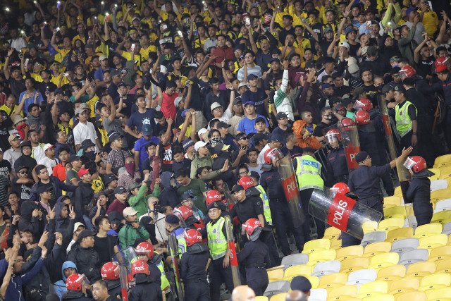 Polisi Malaysia berjaga didekat suporter Malaysia saat pertandingan Timnas Indonesia melawan Malaysia di Stadion Bukit Jalil, Malaysia. Foto: Jamal Ramadhan/kumparan