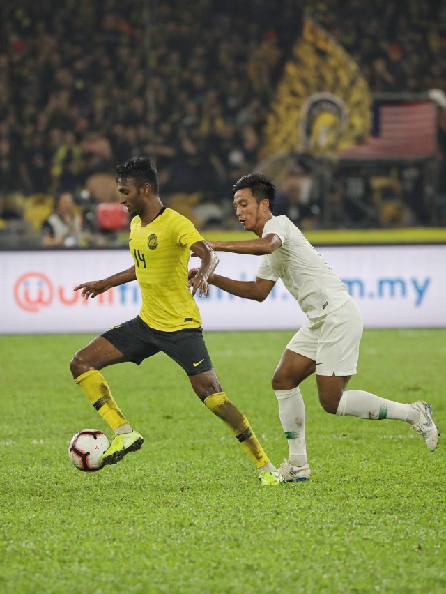 Pemain Timnas Indonesia Bayu Pradana (kanan) berebut bola dengan pemain Timnas Malaysia di Stadion Bukit Jalil, Malaysia.
 Foto: Jamal Ramadhan/kumparan 