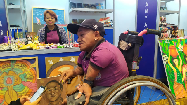 Nyoman Budiarta bersama karya-karya warga Disabilitas yang dipamerkan pada Tenaga Kerja Mandiri (TKM) Expo 2019 - kanalbali/ACH