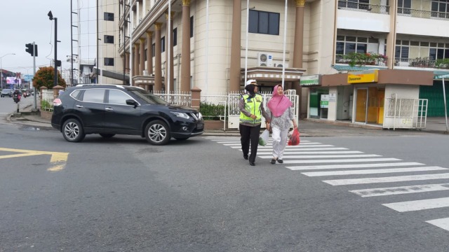 Komisaris Polisi Syarifah Salbiah, Kasat Lantas Polresta Pontianak Kota, membantu menyeberangkan seorang pejalan kaki di Simpang Garuda Pontianak. Foto: Dok Hi!Pontianak