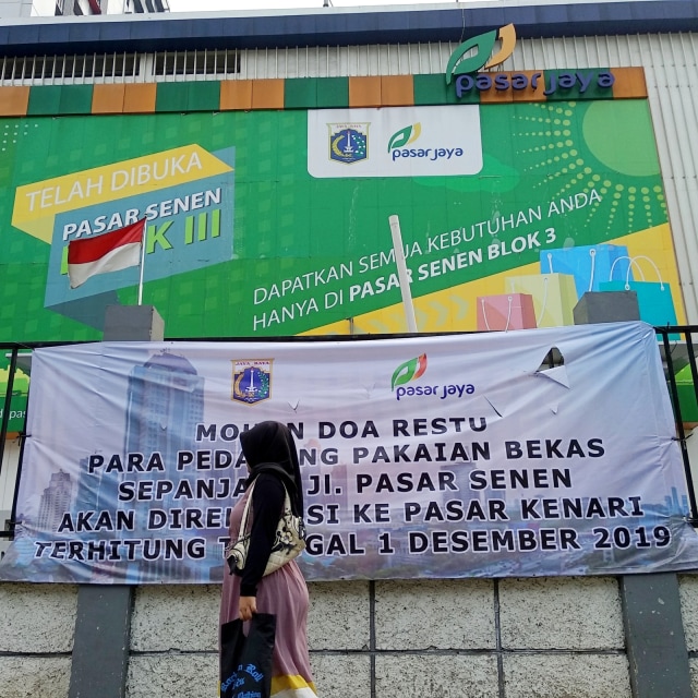 Pejalan kaki melintasi spanduk pemberitahuan terkait relokasi di Pasar Senen Blok III, Jakarta Pusat (23/11/2019).  Foto: Jamal Ramadhan/kumparan