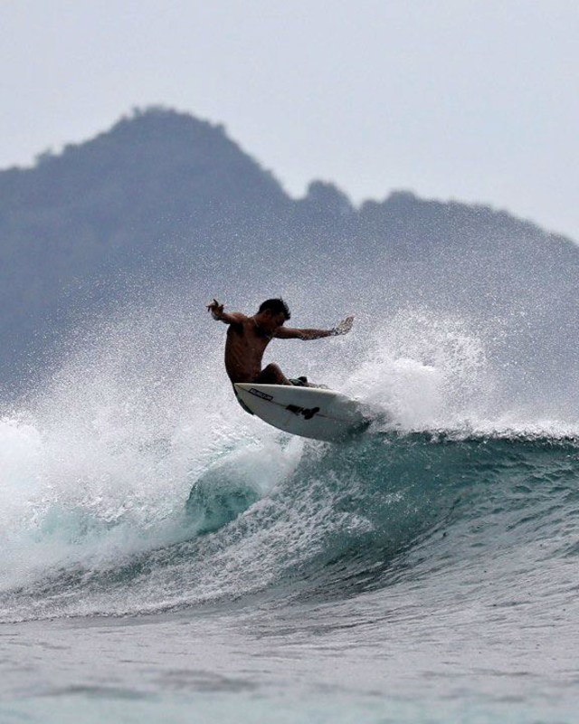 Salah seorang surfer menaiki ombak dalam kegiatan Aceh Surfing Championship 2019. Foto: Windy Phagta/acehkini