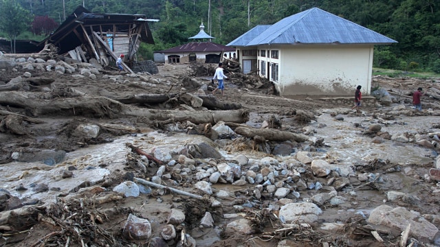 Sejumlah warga berada diantara material sisa banjir bandang di desa Sapan Salak dan Desa Manggih, Senin (25/11). Foto: ANTARA FOTO/Muhammad Arif Pribadi