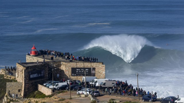 Penonton menyaksikan surfer selama sesi selancar gratis di Nazare, , Rabu (20/11). Foto: Olivier MORIN / AFP