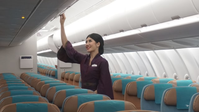 Pramugari Garuda Indonesia memeriksa bagasi di kabin pesawat. Foto: kumparan