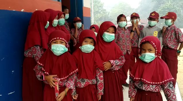 Para pelajar SD di Kolaka Timur gunakan masker karena asap kian menyelimuti areal pekampungan penduduk. Foto: Istimewa.