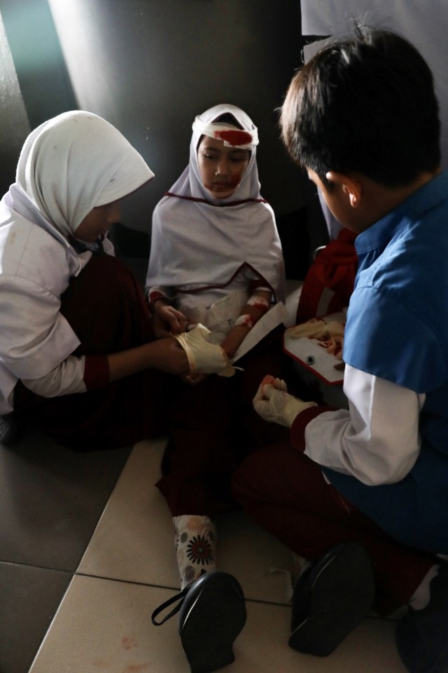 Siswa membantu rekannya yang luka-luka, saat mengikuti simulasi tsunami di Banda Aceh. Foto: Suparta/acehkini