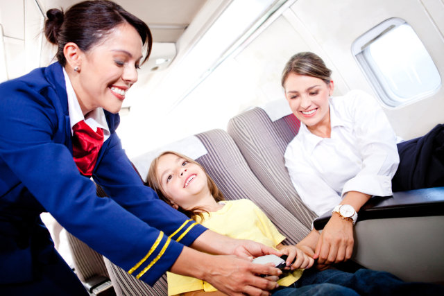 Ilustrasi pramugari membantu penumpang anak mengenakan seat belt Foto: Shutter Stock