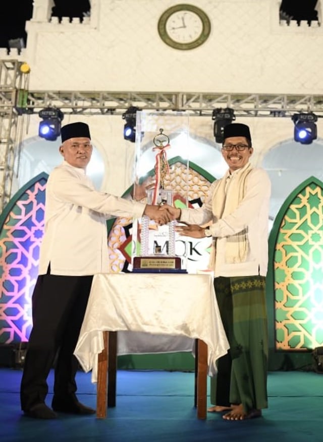 Sekda Aceh, Taqwallah, menyerahkan piala Musabaqah Qiraatil Kutub (MQK) Aceh ke-I Tahun 2019 kepada Kadis Pendidikan Dayah, Usamah Elmadny. Foto: Humas Aceh