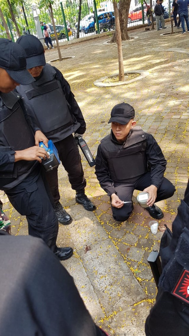 Petugas memeriksa kaca yang diduga serpihan dari jam tangan di sekitar lokasi ledakan di Monas. Foto: Efira Tamara Thenu/kumparan
