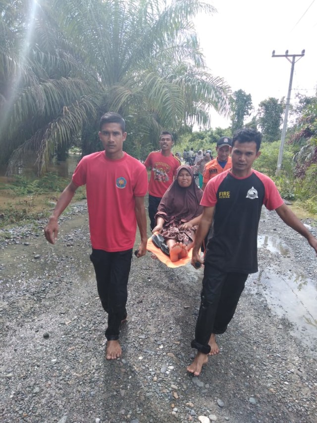 Petugas mengevakuasi warga yang sakit di Kabupaten Aceh Barat dengan menggunakan tandu akibat desanya terendam banjir, Senin (2/12). Foto: Dok. BPBA