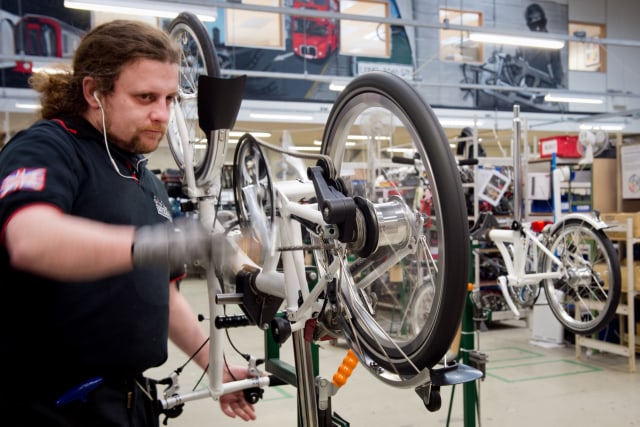 Seorang karyawan perusahaan sepeda Brompton, mengerjakan komponen untuk sepeda lipat di jalur produksi di kantor pusat perusahaan di London. Foto: AFP/LEON NEAL 
