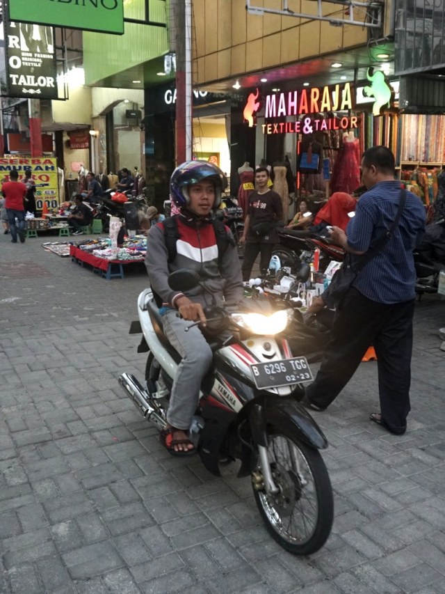 Pengendara motor melintas di samping pedagang di Pasar Baru, Jakarta, Selasa (3/12).  Foto: Iqbal Firdaus/kumparan 