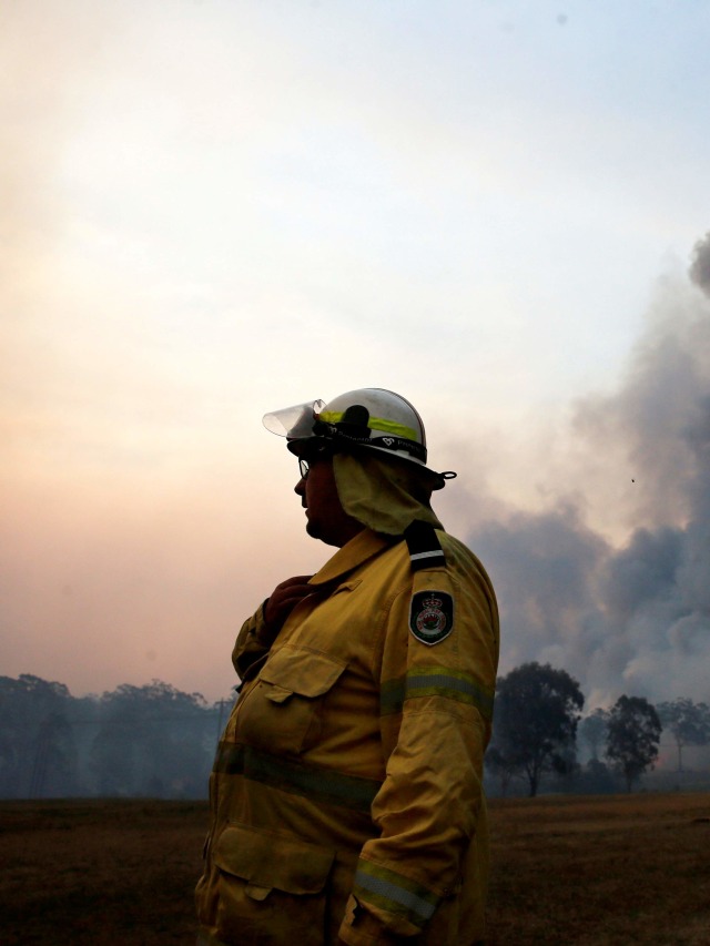 Seorang petugas pemadam kebakaran berbicara menggunakan radio ketika kebakaran hutan di luar kendali di Avery's Lane, Australia, Selasa (3/12). Foto: AAP Image/Darren Pateman/via REUTERS