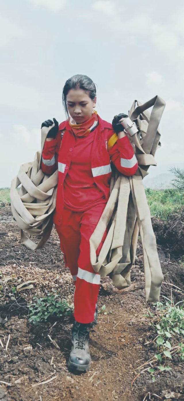 Ni Luh Widiawati, saat memikul selang air untuk digunakan memadamkan api di Kabupaten Kolaka Timur. Foto: Dok Manggal Agni.