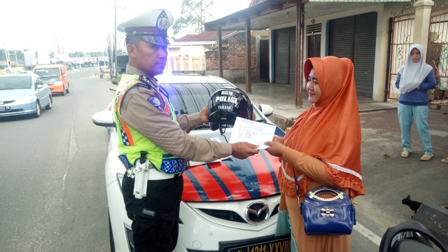 Personil Lantad Polda Babel, saat menyerahkan Helm pinjaman ke salah satu pengguna jalan.