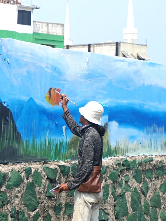 Seorang seniman menggambar mural tentang laut di Penjaringan, Jakarta Utara, Kamis (5/12). Foto: Iqbal Firdaus/kumparan