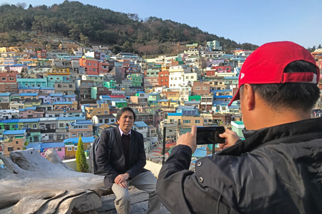 Seorang turis sedang foto dengan latar belakang Gamcheon yang warna-warni. Foto: Adhie Ichsan/kumparan