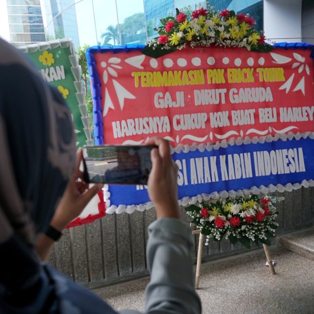 Pengunjung memotret karangan bunga yang menghiasi halaman lobi utama Kementerian Badan Usaha Milik Negara (BUMN) di Jakarta, Jumat (6/12). Foto: Fanny Kusumawardhani/kumparan