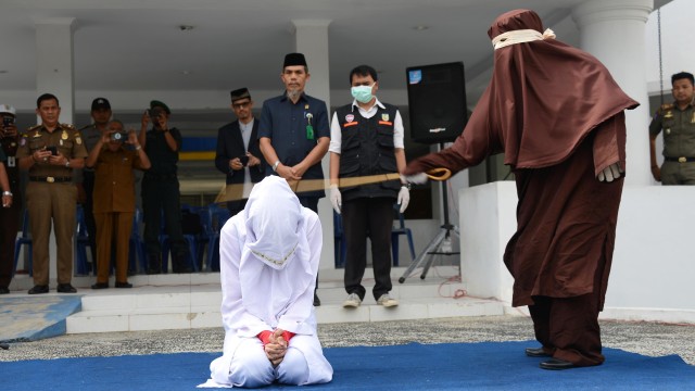 Terpidana pelanggar hukum Syariat Islam (kiri) menjalani eksekusi cambuk di Taman Sari, Banda Aceh, Selasa (10/12). Foto: ANTARA FOTO/Ampelsa