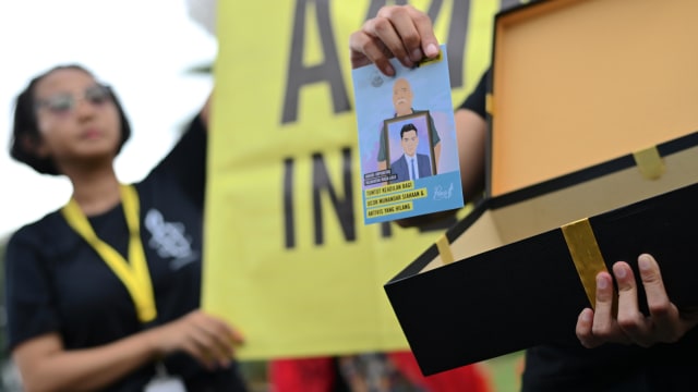 Seorang aktivis dari Amnesty International menunjukkan surat dari publik yang menuntut pejabat penegak hukum untuk bertindak atas pelanggaran hak asasi manusia. Foto: Bay ISMOYO / AFP