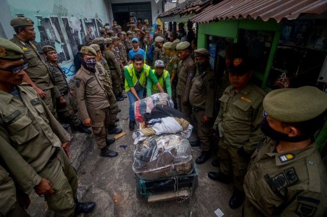 Petugas membawa barang milik warga saat penggusuran permukiman Tamansari di Bandung, Jawa Barat, Kamis (12/12/2019). Foto: ANTARA FOTO/Raisan Al Farisi