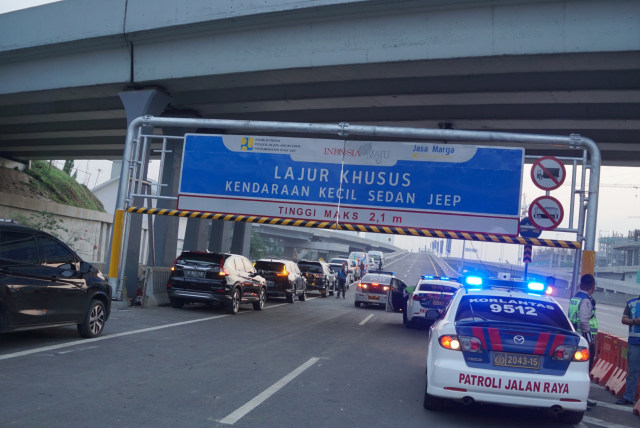 Petugas kepolisian mengatur lalu lintas kenderaan yang akan melewati Tol Layang Jakarta-Cikampek, Minggu (15/12).  Foto: Helmi Afandi Abdullah/kumparan 