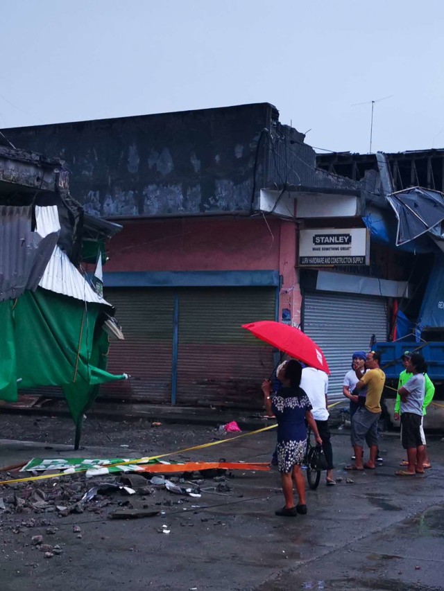 Penduduk melihat sebuah bangunan yang hancur setelah gempa berkekuatan 6,8 di kota Padada di Provinsi Davao del Sur di pulau Mindanao, Filipina selatan. Foto: FERDINANDH CABRERA / AFP