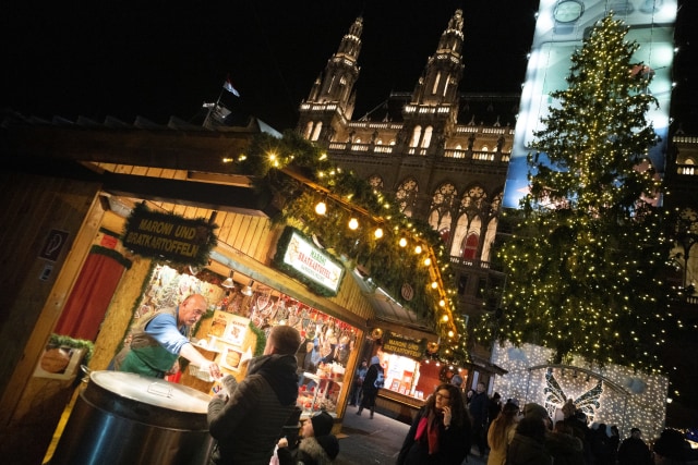 Pengunjung menjelajahi pasar Natal di depan balai kota Wina di Wina, Austria. Foto: AFP/JOE KLAMAR