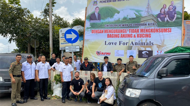 Para pecinta anjing dari Eropa berfoto bersama dengan jajaran pemerintah kota Tomohon, Sulut, di bawah baliho imbauan untuk mengurangi konsumsi daging anjing dan kucing