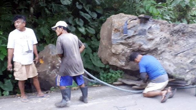 Para pemecah batu di Kabupaten Sitaro, Sulut, tengah mempersiapkan cara untuk memindahkan batu besar yang menghalangi jalan.