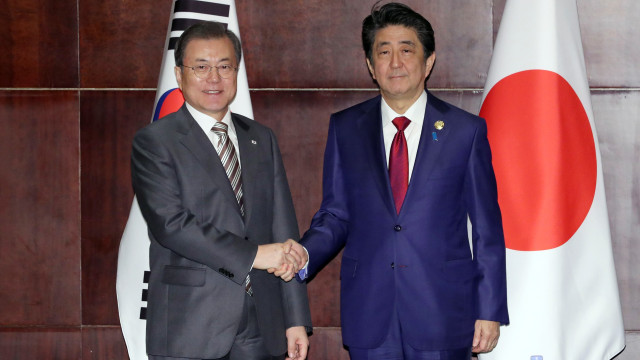 Presiden Korea Selatan Moon Jae-in (kiri) berjabat tanagn dengan Perdana Menteri Jepang Shinzo Abe selama pertemuan di Chengdu, Sichuan, China. Foto: AFP/STR